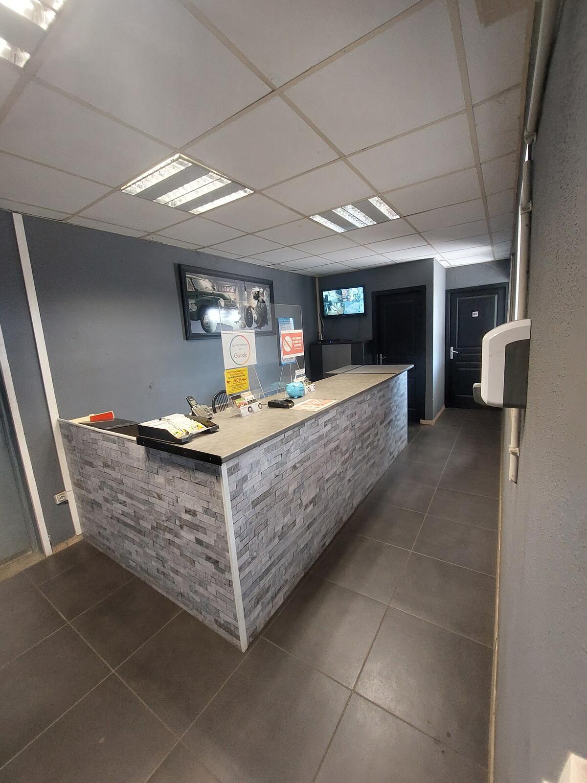Le comptoir d'accueil du magasin de pneus, carrelage gris et murs ardoise