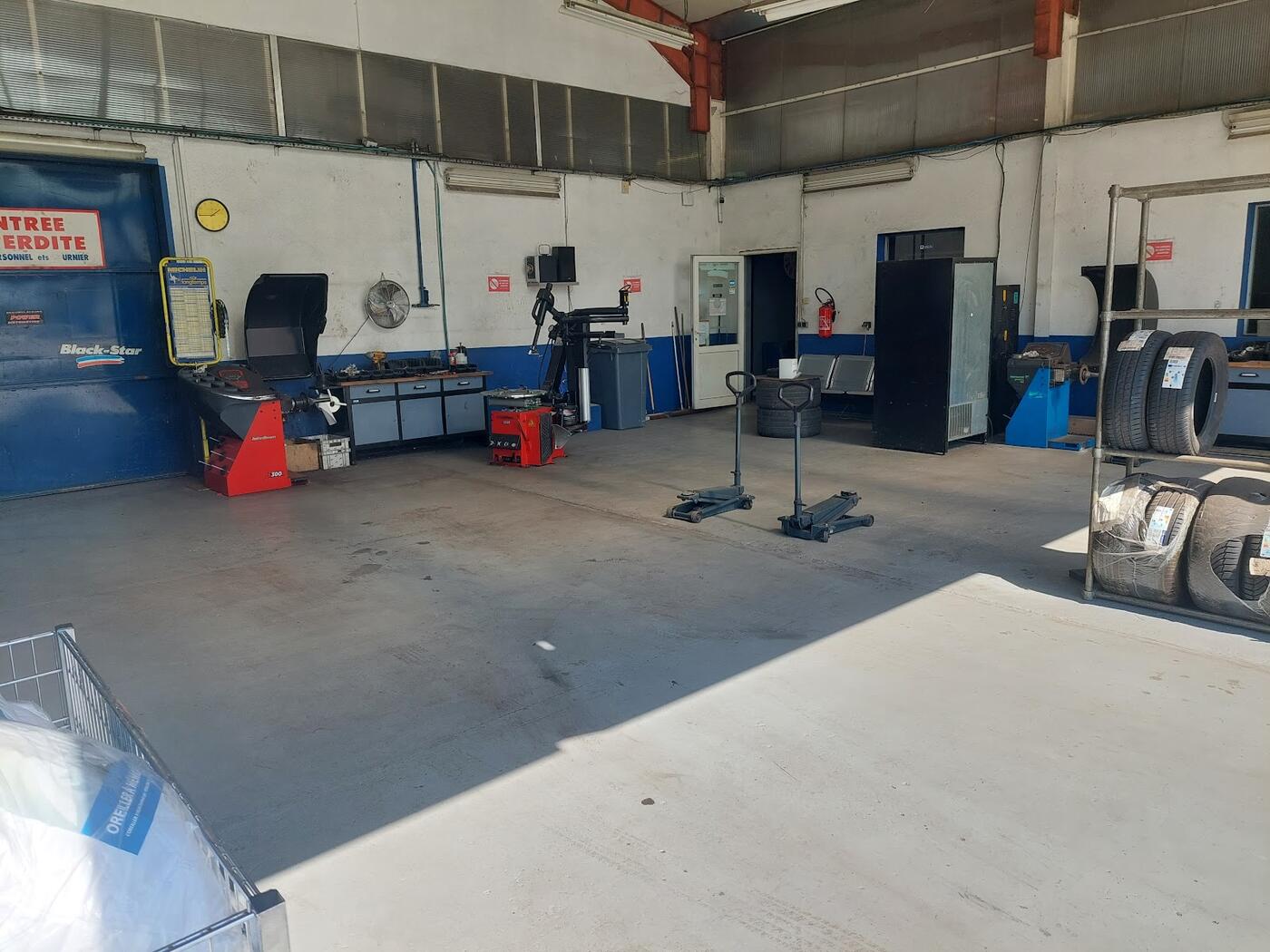 L'atelier vu depuis la porte : équilibreuses, démonte-pneus et sol propre