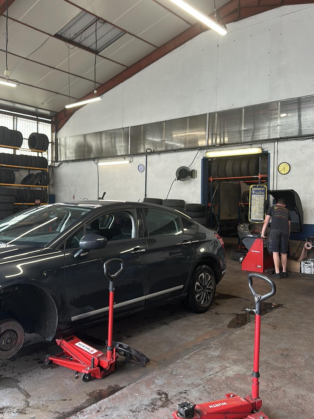 Une berline sur cric rouge pendant un changement de pneus dans l'atelier