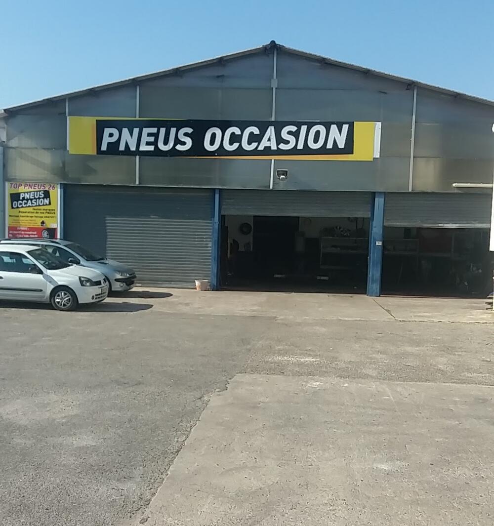 Façade de Top Pneus 26 à Fiancey, bardage gris et enseigne jaune « Pneus occasion », parking devant