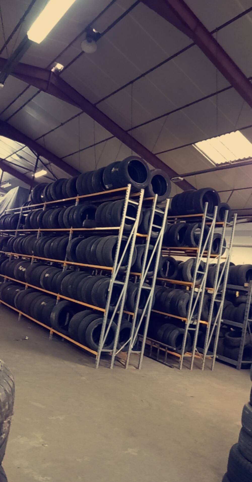 Racks de pneus d'occasion jusqu'à la charpente dans le hangar de Top Pneus 26 à Étoile-sur-Rhône